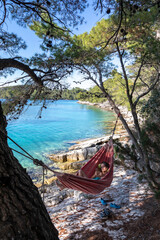 woman with smartphone in hammock on island mljet, croatia