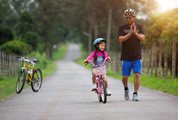 happy family father teaches child daughter to ride a bike in the Park .