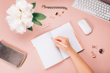 Obraz premium Empty Notebook for writing Dreams and Ideas, with different Stationery, and Big Pink Peony flowers laying on Pink background. Top View. Idea of Girly Office settings. Flat lay style.