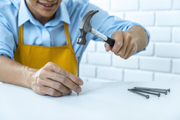 Craftsman doing renovation work at home improvement with using hammer to driving nail on wood