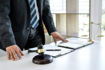Male lawyer working with contract paper and Law books on table in courtroom