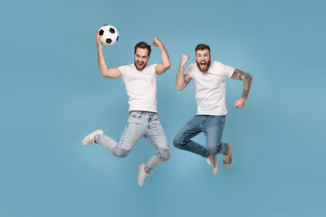 Fototapeta na wymiar Crazy men guys friends in white t-shirt isolated on pastel blue background. Sport leisure lifestyle concept. Cheer up support favorite team with soccer ball, jumping, doing winner gesture, screaming.