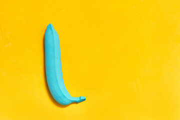 cyan banana painted on a yellow background