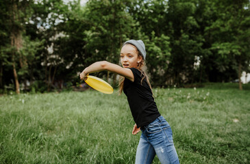 Little girl playing frisbee in the park. Summer time