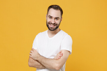 Smiling young bearded man guy 20s in white casual t-shirt posing isolated on yellow background...