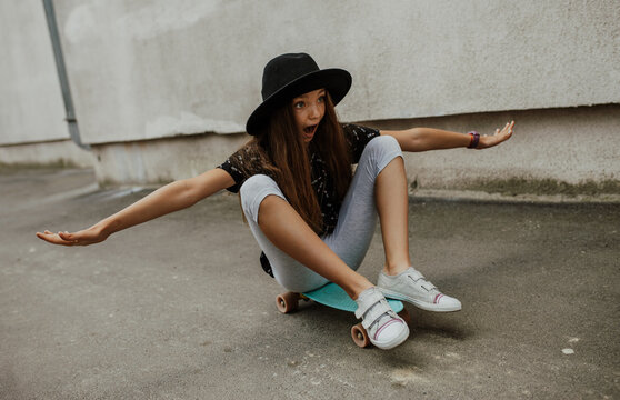 Portrait of little girl with trendy look skating on penny board