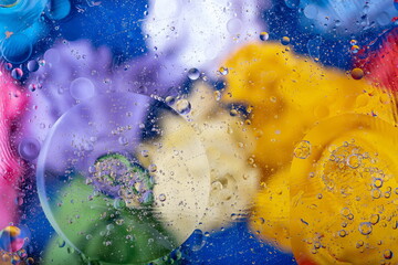 Macro background. Oil drops on water with colorful glass