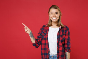 Smiling young blonde woman girl in casual checkered shirt posing isolated on red wall background...