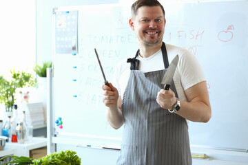 Handsome young man looking at camera and smiling while standing near whiteboard with recipe