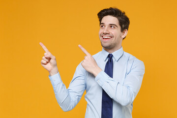 Funny young business man in classic blue shirt tie posing isolated on yellow background studio portrait. Achievement career wealth business concept. Mock up copy space. Point index fingers aside up.
