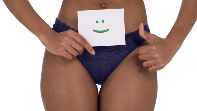 Close-up of unrecognizable woman in blue lace panties holding a sing with positive green smile and showing thumb up. Female menstrual cycle concept. Isolated, on white background