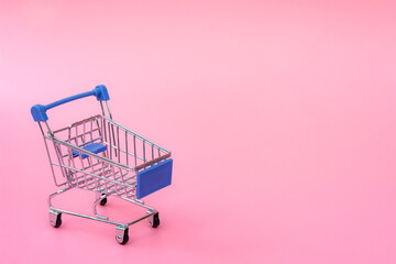 Shopping concept : Blue shopping cart on pink background. online shopping consumers can shop from...