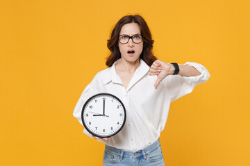 Perplexed young brunette business woman in white shirt glasses isolated on yellow wall background...