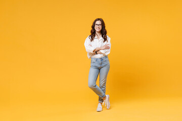 Fototapeta na wymiar Smiling young brunette business woman in white shirt glasses isolated on yellow wall background studio portrait. Achievement career wealth business concept. Mock up copy space. Holding hands crossed.