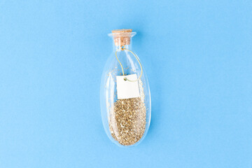 Flat lay. Beautiful glass decorative bottle with gold glitter and empty blank for text inside. Top view. Place for your text.