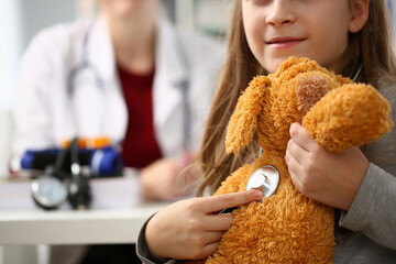 Close up of adorable child examining toy with stethoscope in clinic