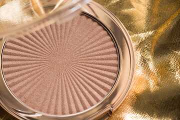 Highlighter, makeup, gold, light. Highlighter for makeup on a gold background. Cosmetic macro. Macro photography of highlighter for makeup on a gold background.
