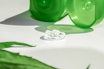 A tube of green with a transparent aloe vera gel. On a white background among green leaves