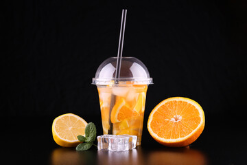 Lemonade to go cup with mint, orange and lemon on black background, isolated