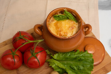 Casserole with mushrooms and cheese in the pot on the table. Julienne with chicken and mushrooms.