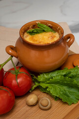 Casserole with mushrooms and cheese in the pot on the table. Julienne with chicken and mushrooms.