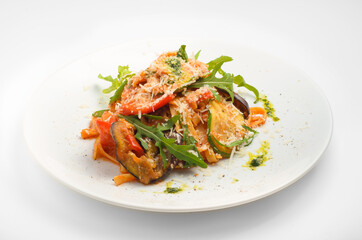 Tagliatelle with grilled vegetables and pesto. Beautiful serve on a white plate, on a white background. For use in menu design and food delivery service.