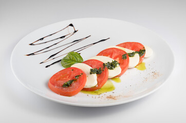 Caprese Salad - a light meal of tomatoes, mozzarella, olive oil and basil. One of the varieties of antipasti. The national Italian dish. For use in menu design and online food catalog