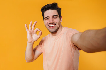 Photo of happy handsome man showing ok sign while taking selfie photo