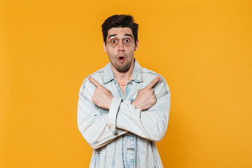 Photo of surprised young man in eyeglasses pointing fingers aside