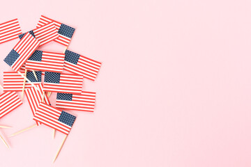 Many miniature american flags from toothpicks at left on pink background, flat lay. Celebration memorial day in America. 4th of july, usa independence day. Copy space for text.