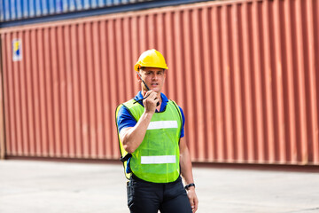 foreman maneger working through a radio communication with the workers in the container yard at port of import and export goods.