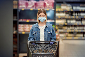 Young girl in a shop with a trolley. Safe shopping during an epidemic.