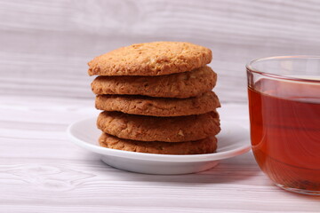 Fototapeta na wymiar homemade cookies and a glass cup of black tea on the rustic white wooden background. close up