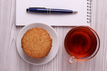 homemade cookies, a notebook with empty space and a pen, glass cup with black tea. minimalism style. top view