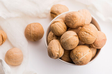 Walnuts in a white ceramic bowl on a white background