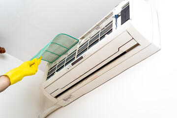 Male technician cleaning air conditioner indoors/ Closeup of hands repairman changes the filter and...