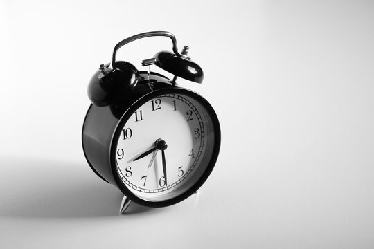 Black vintage alarm clock on table. White background. Wake up concept. An image of a retro clock showing 08:30 pm/am.