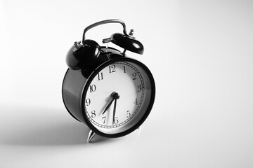 Black vintage alarm clock on table. White background. Wake up concept. An image of a retro clock...