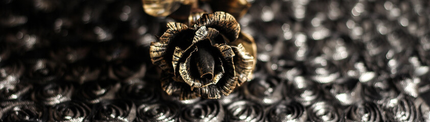 An iron rose on a shiny dark background. Bronze flower.