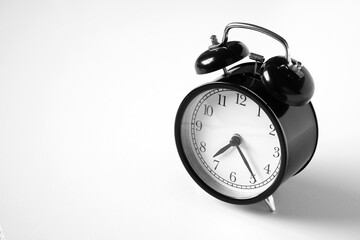 Black vintage alarm clock on table. White background. Wake up concept. An image of a retro clock...