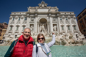 Coppia di turisti anziani lancia una moneta nella fontana di Trevi a Roma - obrazy, fototapety, plakaty