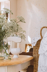 Summer interior with porcelain cup on the wooden table and basket with lace fabric. 