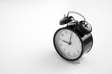 Black vintage alarm clock on table. White background. Wake up concept. An image of a retro clock...