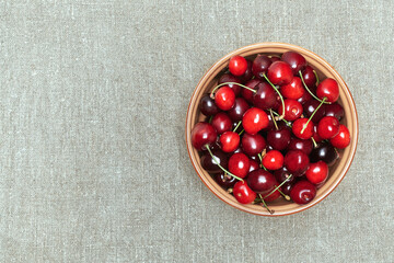 Ripe sweet cherries in a plate, on canvas background