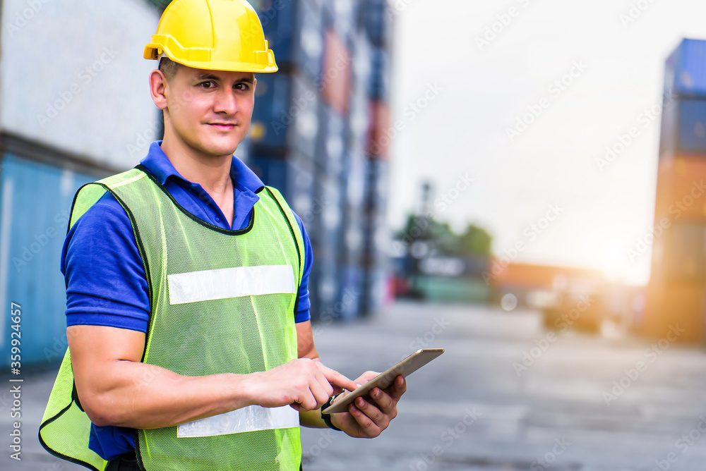 Wall mural young confident caucasian man engineer using digital tablet and wearing yellow safety helmet and che