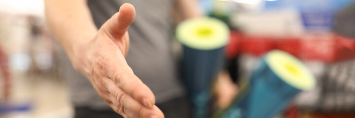 Guy seller in sportswear holds out his hand