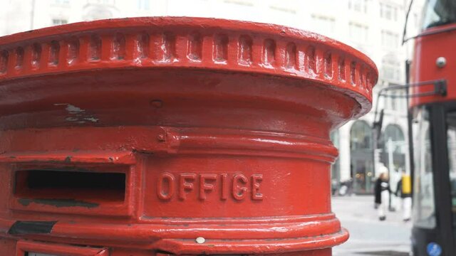 A close up view of a red post box on a street.