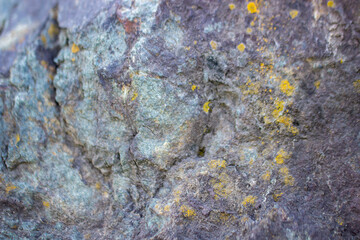 The background is the texture of a stone rock. partially blurred image. Blue stone with golden inclusions