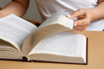 Naklejka premium A woman is reading a book. Hands are holding a book. Beautiful manicure. A student is studying a textbook. The concept of education and study of information