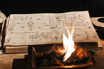 Occult white magic ritual of fire using grimoire, old book, candles